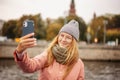 Red-haired woman in glasses traveler in a hat and jacket chatting on a smartphone while taking a selfie in Moscow, on Kremlin