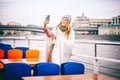 Red-haired woman in glasses traveler in a hat and jacket making a selfie in Moscow on a pleasure boat on the river in the city