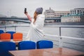 Red-haired woman in glasses traveler in a hat and jacket making a selfie in Moscow on a pleasure boat on the river in the center