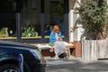 Red haired woman outdoors uses mobile phone sitting on the bench