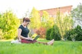 Red-haired woman sits in green grass with a puppy in the park and online shopping. The girl maintains a social distance