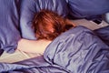 Red-haired woman sleeping in bed next to the phone, lifestyle Royalty Free Stock Photo