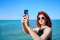 Red-haired woman takes selfie on smartphone camera. Royalty Free Stock Photo