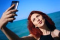 Red-haired woman takes selfie on smartphone camera. Royalty Free Stock Photo