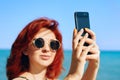 Red-haired woman takes selfie on smartphone camera. Royalty Free Stock Photo