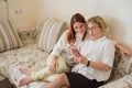 Red-haired woman teaches an elderly mother how to use a smartphone. Mother and adult daughter dressed in white blouses are sitting
