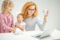 Red-haired woman watching film while her children entertaining with a cat Royalty Free Stock Photo