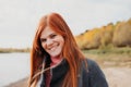 red haired woman wearing coat and walking on a seashore. autumn portrait. lifestyle, real people. beautiful ginger hair