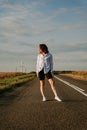 A red-haired woman in a white shirt walks along the road among the fields Royalty Free Stock Photo