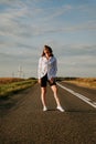 A red-haired woman in a white shirt walks along the road among the fields Royalty Free Stock Photo