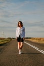 A red-haired woman in a white shirt walks along the road among the fields Royalty Free Stock Photo