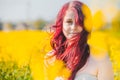 red haired woman in yellow rapeseed field looking in camera with a little smile Royalty Free Stock Photo