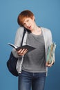 Red-haired young good-looking male student in casual outfit with black backpack holding lot of books and notebook in Royalty Free Stock Photo