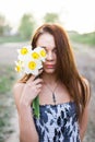 Red-haired young lady in floral dress with bouquet of daffodils Royalty Free Stock Photo