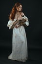 Red-haired young woman in a vintage gold dress with bare shoulders with a dry bouquet in hands on a black background in full growt Royalty Free Stock Photo