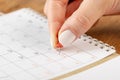 Beautiful female Hand with manicure pushes a red pin on a calendar 13 day Royalty Free Stock Photo