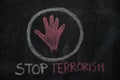 Red hand shape and stop terrorism text in the circle on black chalkboard