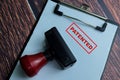 Red Handle Rubber Stamper and Patented text above paperwork isolated on wooden background