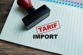 Red Handle Rubber Stamper and Tarif Import text above book isolated on wooden background Royalty Free Stock Photo