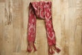 Red handmade weaving scarf in wooden background.