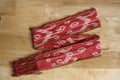 Red handmade weaving scarf in wooden background.