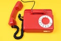 A red handset lies next to a landline telephone on a yellow background. An old Soviet vintage telephone.