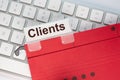 Red hanging folder on a keyboard has a tab with the word clients on it Royalty Free Stock Photo