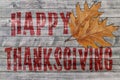 Red Happy Thanksgiving written on wooden board background with two leaves Royalty Free Stock Photo