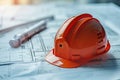 A red hard hat and drafting tools on top of architectural blueprints, representing construction and engineering planning