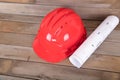 Red hard hat and a roll of drawings on the table Royalty Free Stock Photo