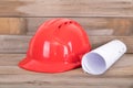 Red hard hat and a roll of drawings on the table Royalty Free Stock Photo