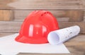 Red hard hat and a roll of drawings on the table Royalty Free Stock Photo