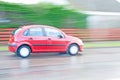 Red hatchback car driven in the rain.