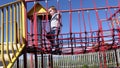 Red headed boy playing on a rope bridge at a playpark