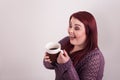 Red headed female holding cup of warm coffee looking at mug excited look on her face Royalty Free Stock Photo