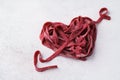 Red heart and arrow made of beetroot vegan pasta.