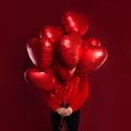 Red heart balloons in female hands on red background. Love, valentines people and Valentine`s day concept Royalty Free Stock Photo