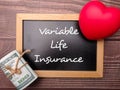Red heart and banknotes with the word Variable Life Insurance. Business concept.