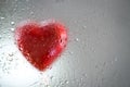 Red heart behind a wet window Royalty Free Stock Photo