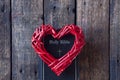 Red heart on a black bible. On a wooden background. View from above.