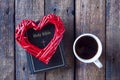 Red heart on a black bible. White cup with tea or coffee. On a wooden background. View from above.