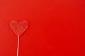 Red heart with brilliant dots on a white stick on a wooden surface