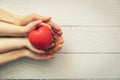 Red heart in child and adult hands on white wooden background. concept of health, organ donation, family insurance Royalty Free Stock Photo