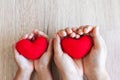 Red heart in child hands and parent hands on wooden table background Royalty Free Stock Photo