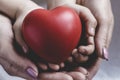 Red heart in child and parent hands with love and harmony. Mom and daughter holding red heart togethe