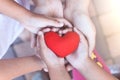 Red heart in child and parent hands with love and harmony