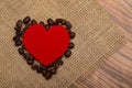 Red heart and coffee beans on a napkin of natural burlap on the table Royalty Free Stock Photo