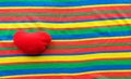 Red heart on a colored striped fabric. rainbow background, banner with place for text. bright texture. love Royalty Free Stock Photo