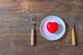 Red heart on dish and table knife and fork on wood Royalty Free Stock Photo