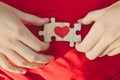 Red heart is drawn on the pieces of the puzzle in male hands on red background. Love concept. St. Valentine day Royalty Free Stock Photo